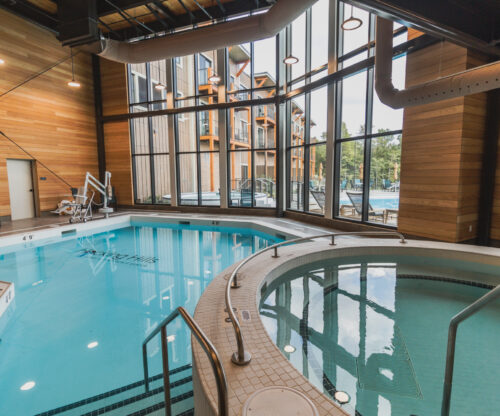 Indoor Pool and hot tub with large windows bringing in natural light